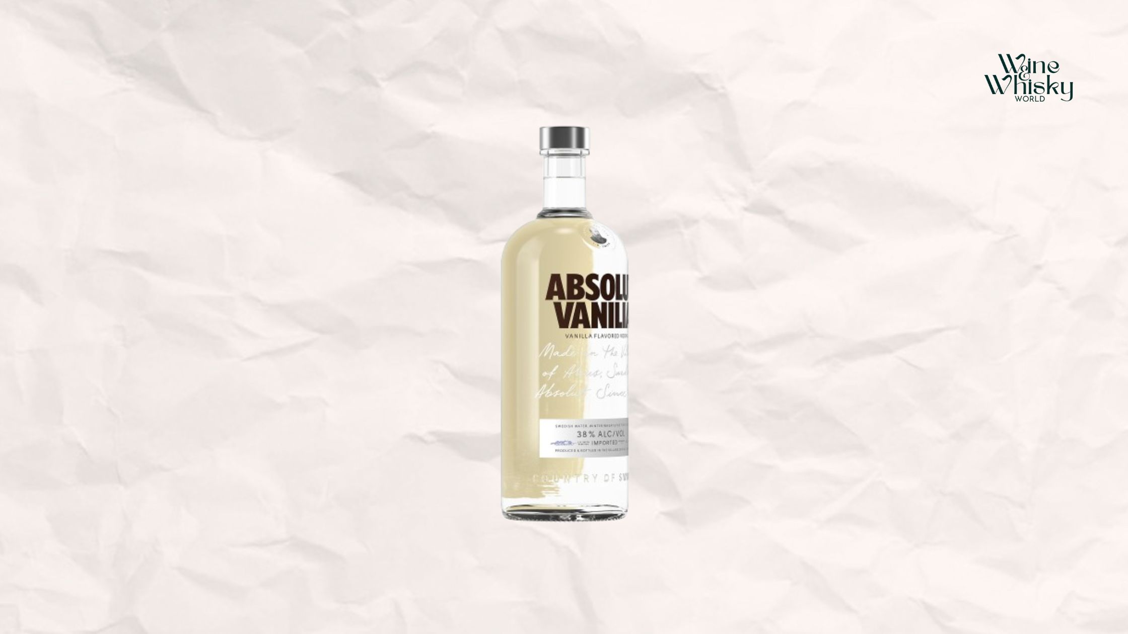 Clear glass bottle of Absolut Vodka with brown and black text on the label, reading 'Absolut Vodka', displayed against a crumpled white paper background with the Wine Whisky World logo in the top right corner.